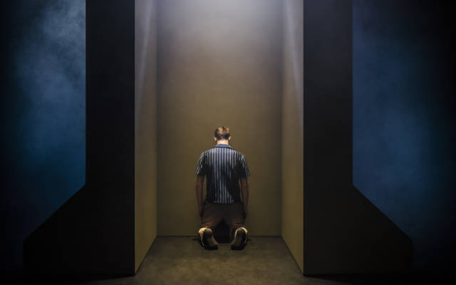 Production photo for Grand Finale, a man kneels, facing away from the camera.