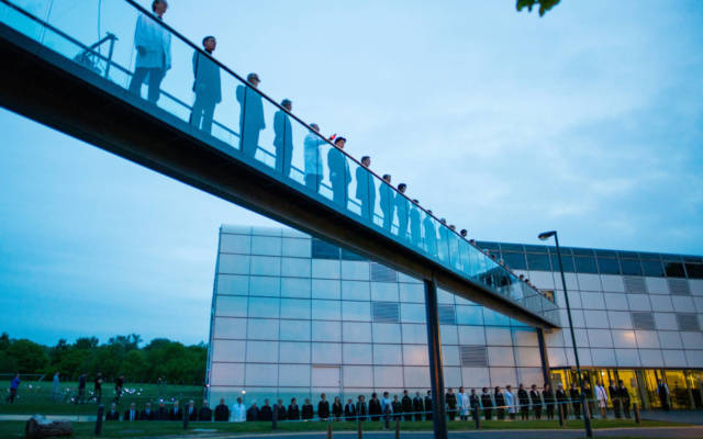 Photo from NNF15 show The Observatory, a long line of people stand on a raised walkway leading to the Sainsbury Centre for Visual Arts.