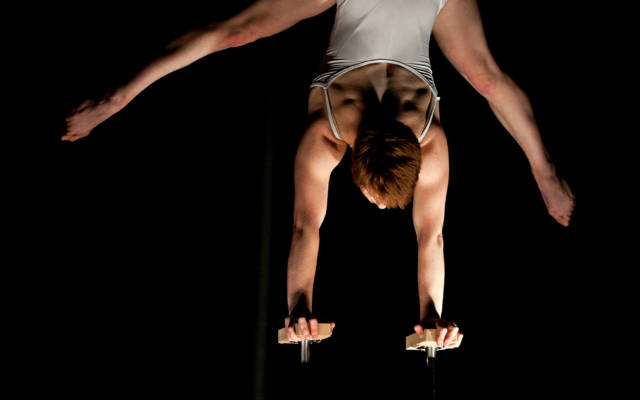 Photo from NNF12 show How Like An Angel, a circus performer stands on her hands on two small plinths.