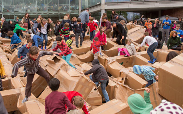 Photo from NNF14 show The Peoples Tower, tens of people stomp over the remains of a large cardboard structure.