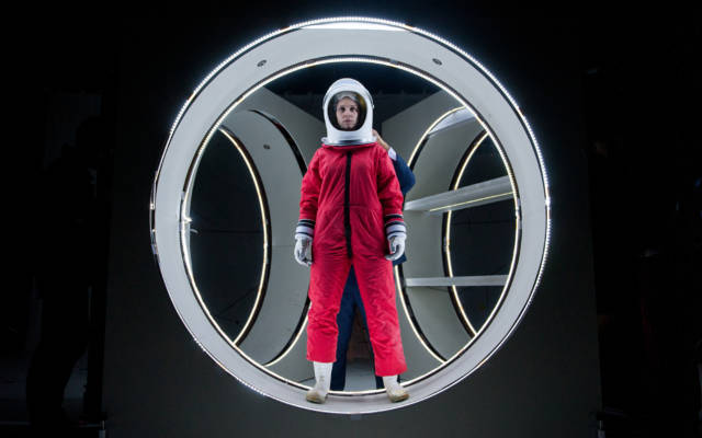 Photo from NNF14 show Pioneer, a woman dressed in a red spacesuit and white space helmet.