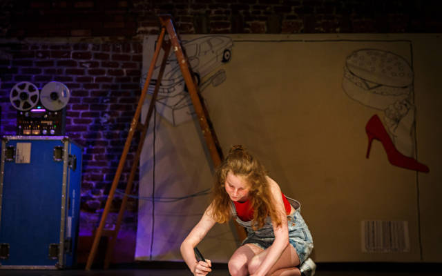 Photo from NNF16 show Wild Life, a woman sits on stage, drawing on a large piece of paper.
