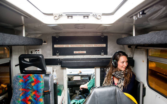 Photo from NNF13 show The Kindness of Strangers, a woman wearing a pair of headphones sitting in the back of an ambuland & gazing out of the window.