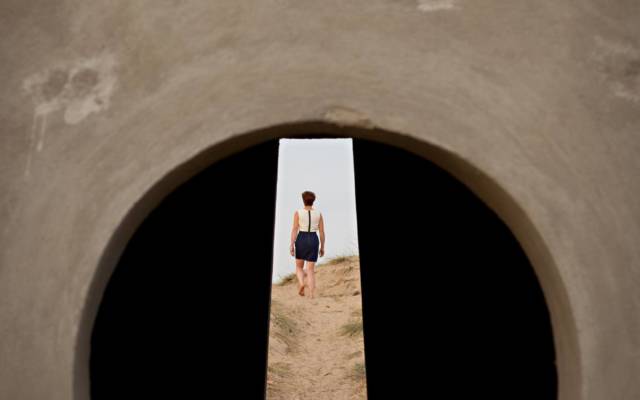 An image taken through a hole, you can see a woman walking away from the camera.