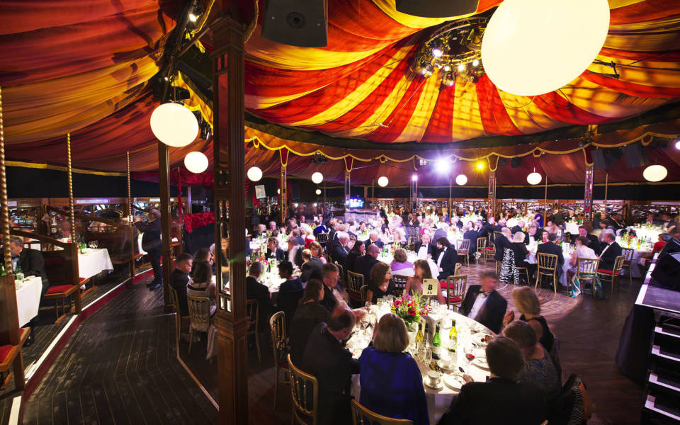 Picture from the NNF17 Gala, inside the Adnams Spiegeltent. People sit around circular tables.