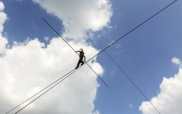 A man walks across a high tight-rope