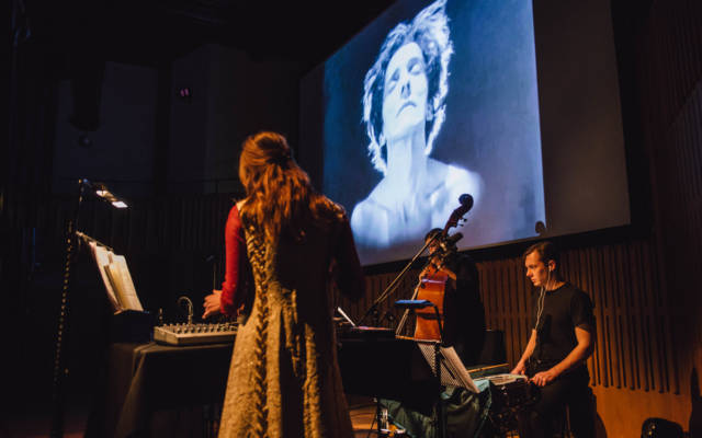 Haley Fohr and band perform in front of a projection of Salomé