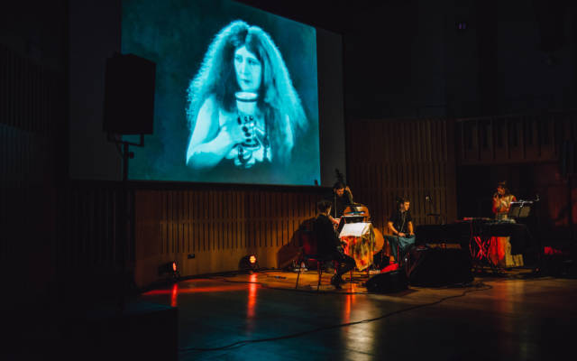 Haley Fohr and band perform in front of a projection of Salomé