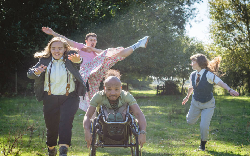 Photo: Four people dancing outside in a field.