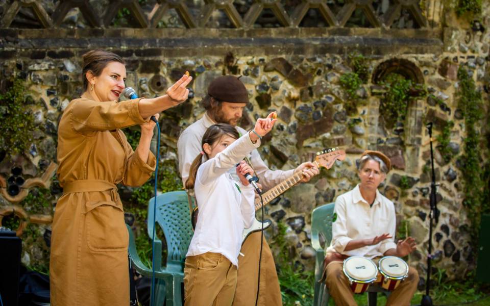 Four artists from Curios making music together. One playing the bongos, one electric guitar, two singing into microphones.