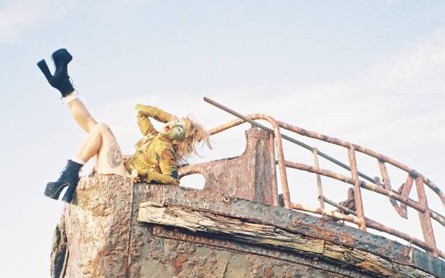 Oozing Gllop lays on a shipwrecked boat, with their right leg pointed in the air.