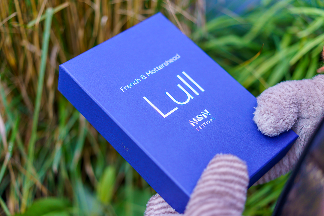 Blue box with 'Lull' in silver text on the front, held by gloved hands.