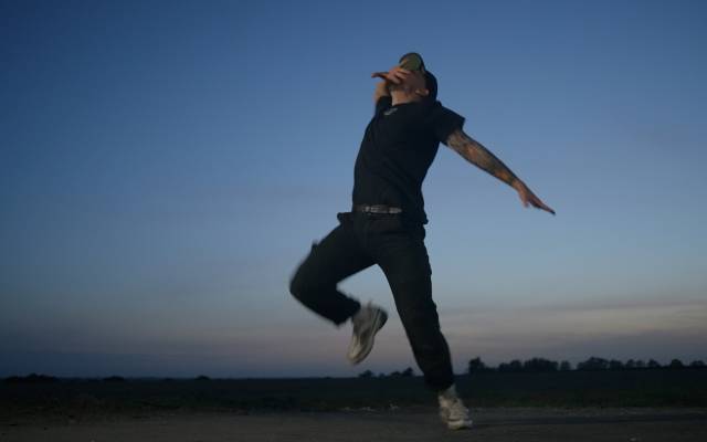 A man dances in a flat landscape at twilight