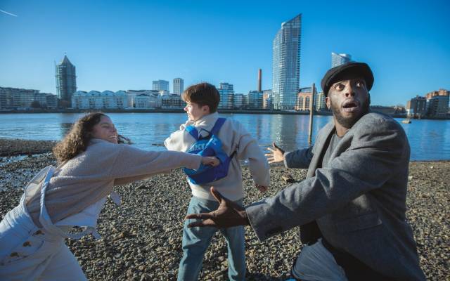 Three people dancing by a river.