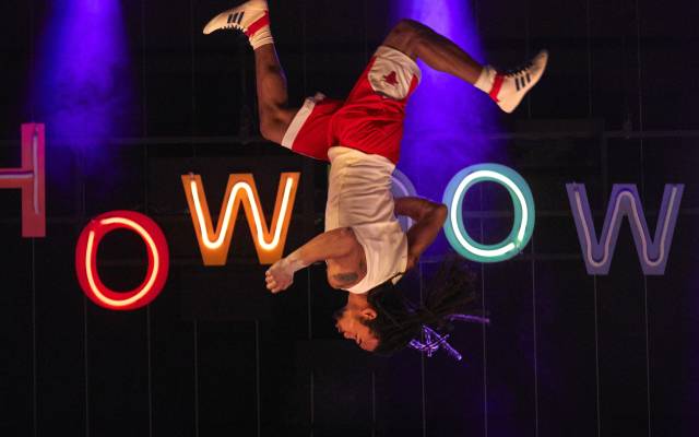 A circus performer pictured halfway through a flip, upside down.