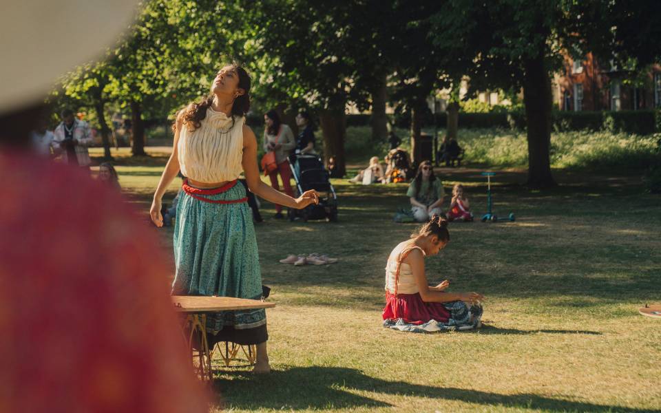 Two women dance in a green park.