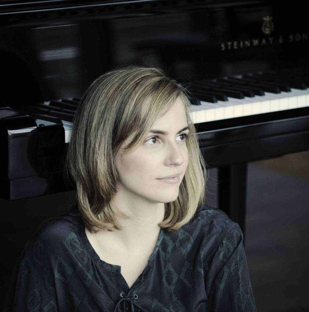 A white woman looks to the right, with a piano in the background.